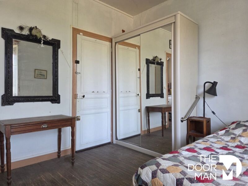 Chambre de l’appartement CAP NORD Chambre d'appartement avec miroir et table en bois, murs clairs et sol en bois.