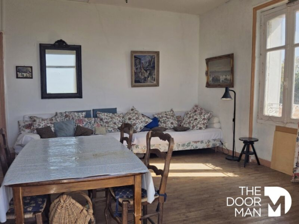 Intérieur d'un appartement avec un salon et une table à manger, décoré de coussins et de tableaux.