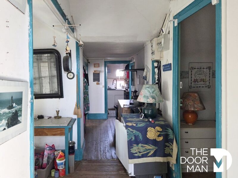 Intérieur d’un appartement à Mesquer Intérieur d'un appartement avec couloir menant à une cuisine, décoré de manière vintage.