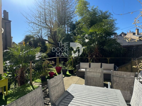 Jardin avec mobilier de jardin et plantes tropicales, maison en ville à Laval.