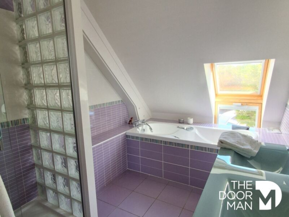 Salle de bain moderne avec baignoire et fenêtre à Vieille-Église-en-Yvelines.