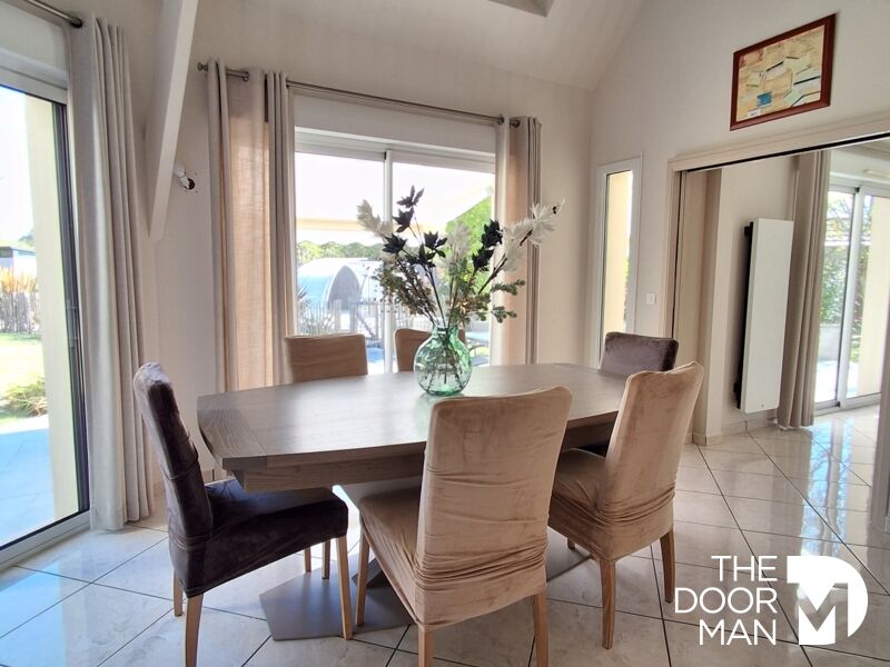 Salle à manger moderne Salle à manger d'une maison moderne avec une table et des chaises, fenêtres laissant entrer la lumière.