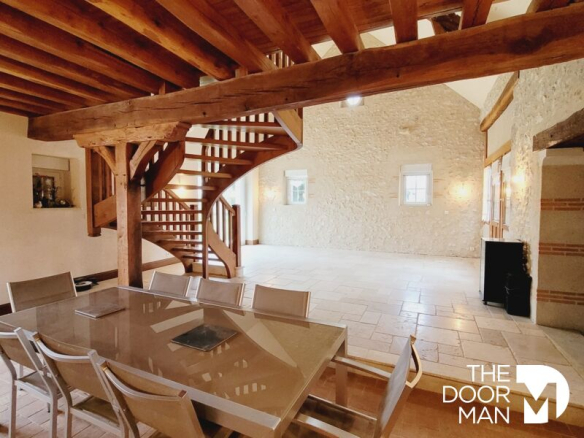 Interior of a restored farmhouse with exposed beams and a large dining room.