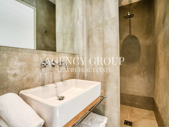 Luxurious concrete bathroom with a white rectangular sink, towel, and an open walk-in shower.