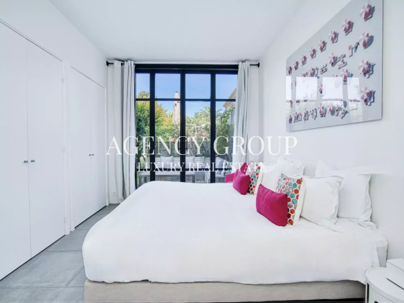 Bright luxury bedroom with a large window, white bed, and colorful throw pillows; minimalist wardrobes along the left wall and abstract art on the right wall.