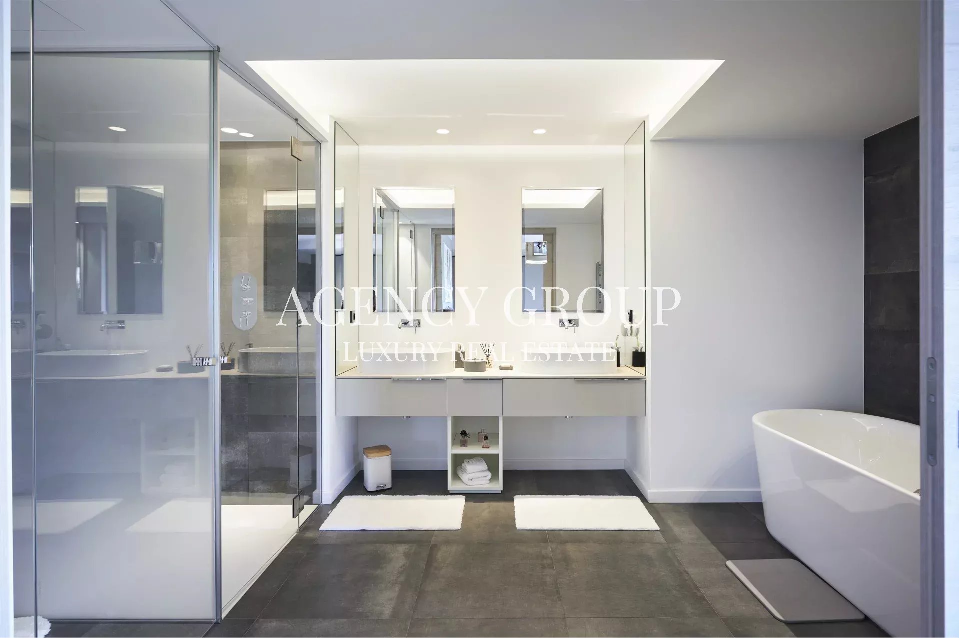 Modern, luxurious bathroom with a glass-enclosed shower, double vanity, and a freestanding oval tub in a white-gray color palette.