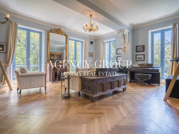 Luxurious living room with blue walls, tall windows, and an ornate chandelier over a carved wooden coffee table.
