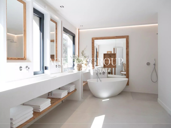 Bright minimalist bathroom with a freestanding oval tub, wooden-framed mirrors, and open-shelf towel storage.