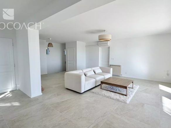 Bright open living room with a white sectional sofa, wooden coffee table, and sliding glass doors to a balcony.