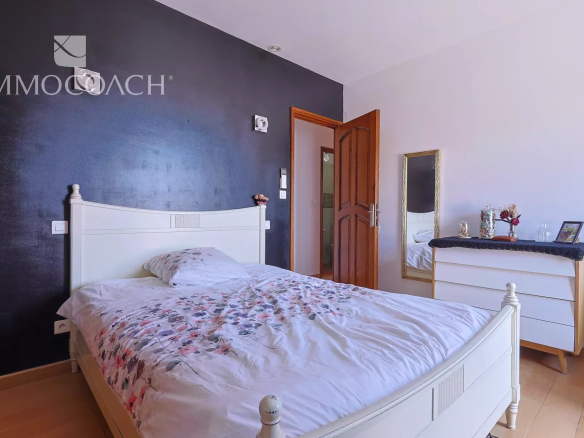 White wooden bed with floral duvet in a bedroom with a dark blue accent wall.