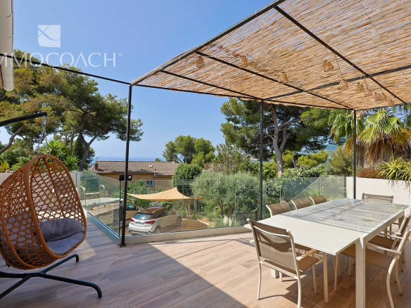 Terrasse d'une maison rénovée à Carqueiranne avec vue sur la nature, mobilier moderne et espace de repas.