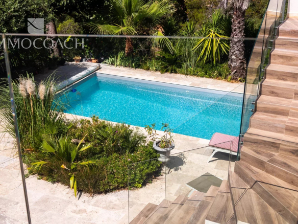 Vue d'une piscine entourée de végétation dans une maison à Carqueiranne.