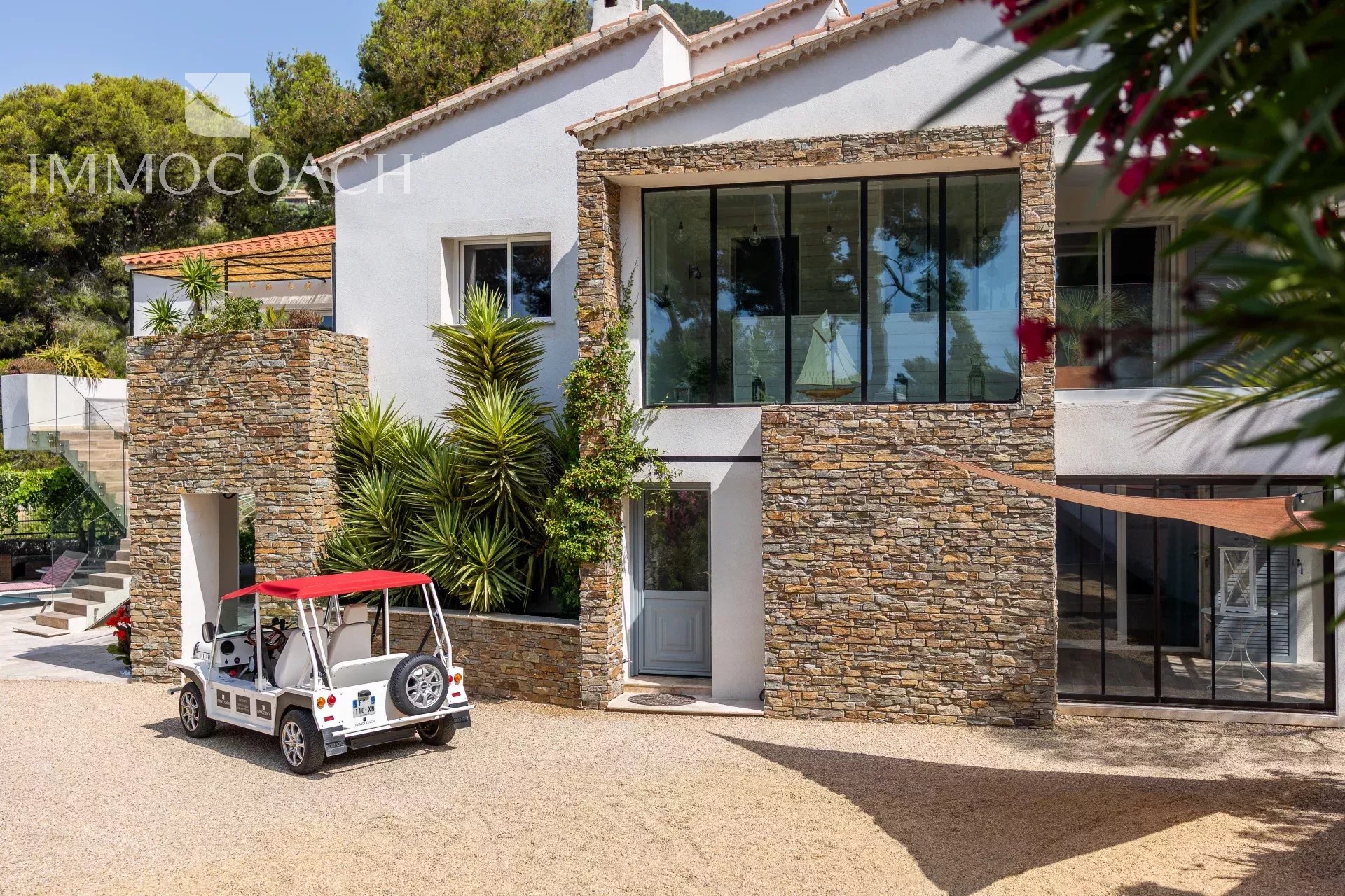 Maison rénovée à Carqueiranne avec façade en pierre et véhicule électrique devant.