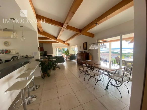 Intérieur d'une villa contemporaine avec cuisine ouverte et salle à manger, vue sur la mer.