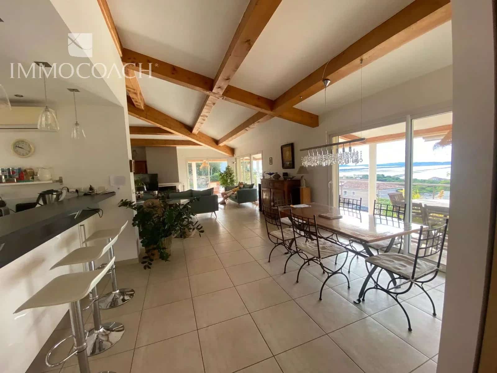 Intérieur d'une villa contemporaine avec cuisine ouverte et salle à manger, vue sur la mer.