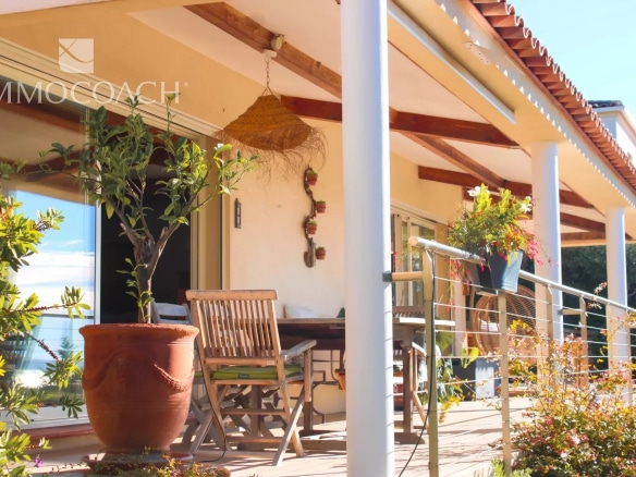 Terrasse d'une villa contemporaine avec mobilier extérieur et plantes, vue dégagée.