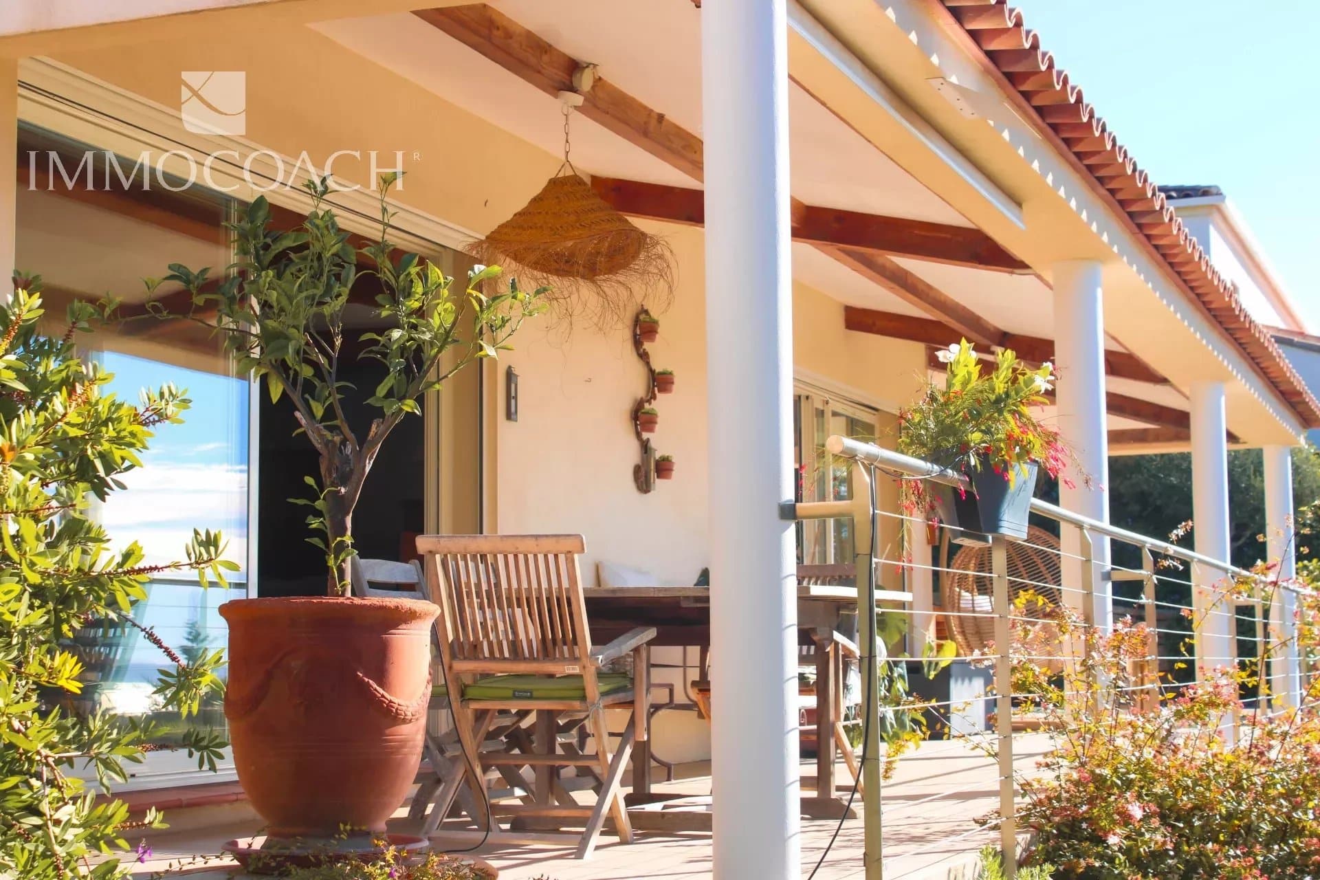Terrasse d'une villa contemporaine avec mobilier extérieur et plantes, vue dégagée.