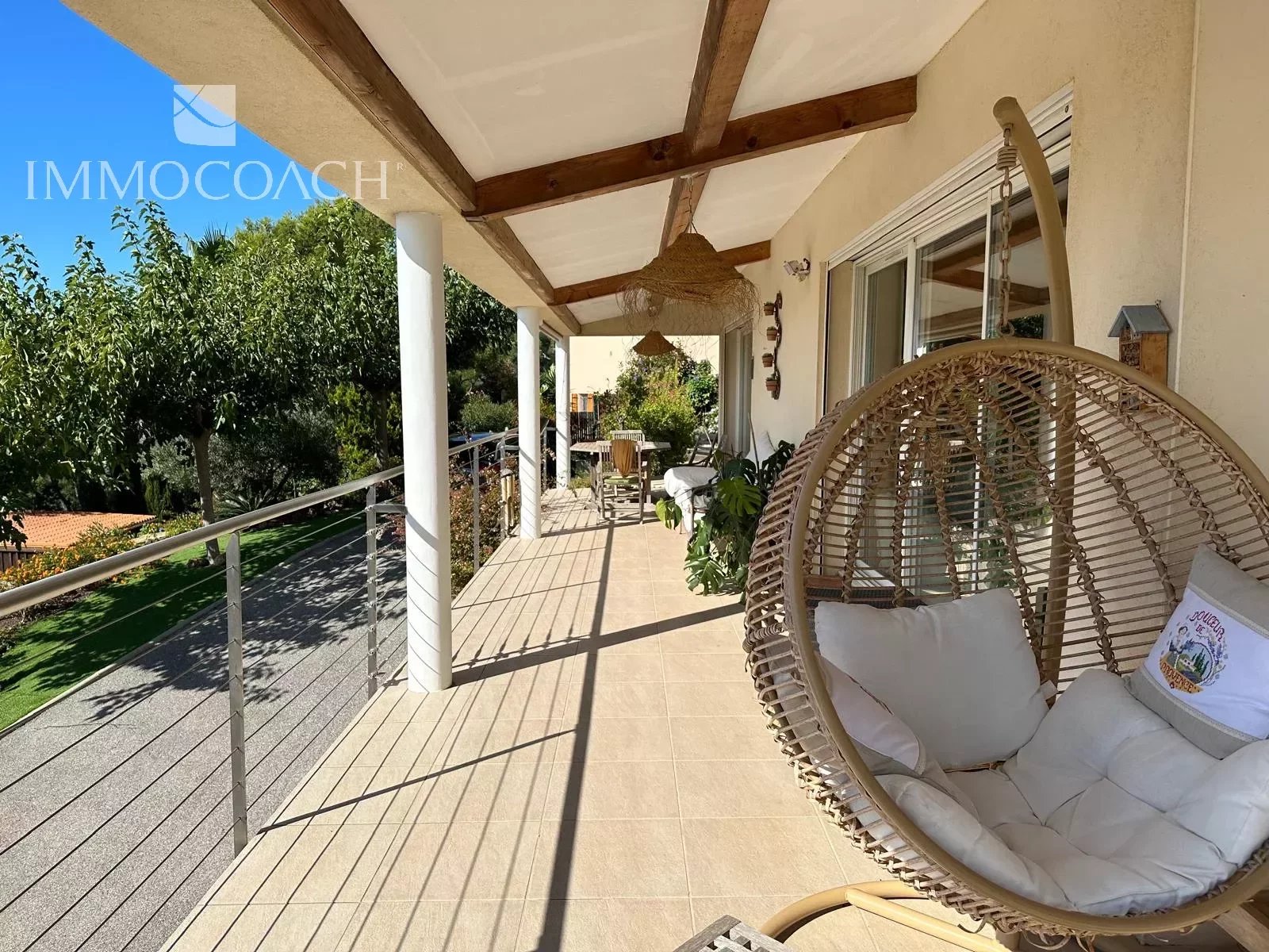 Terrasse d'une villa contemporaine avec vue sur jardin et mer à Hyères, mobilier de jardin visible.