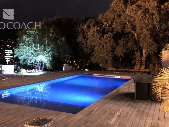 Californian villa with a pool lit at night, surrounded by trees in Carqueiranne.