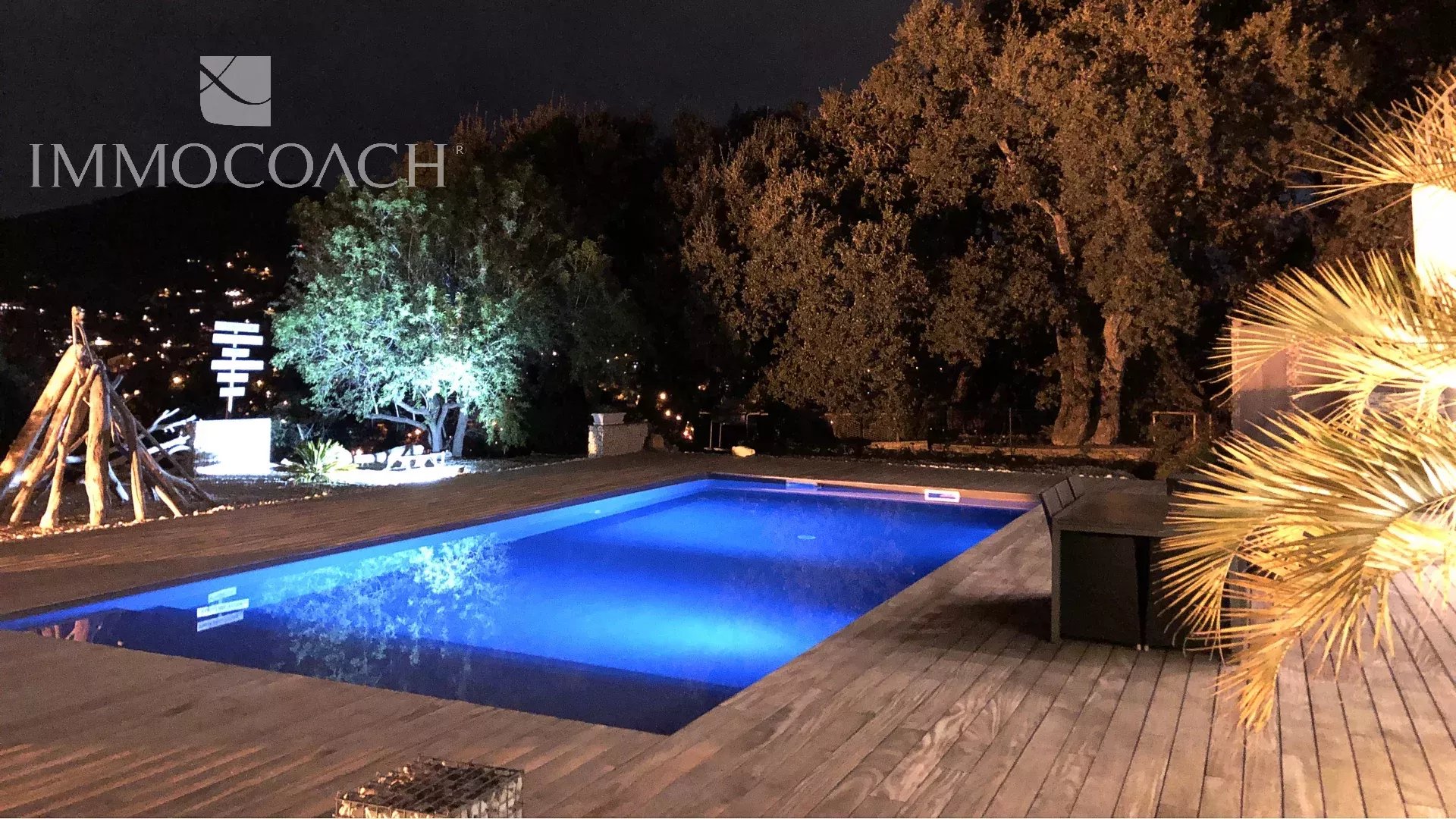 Californian villa with a pool lit at night, surrounded by trees in Carqueiranne.