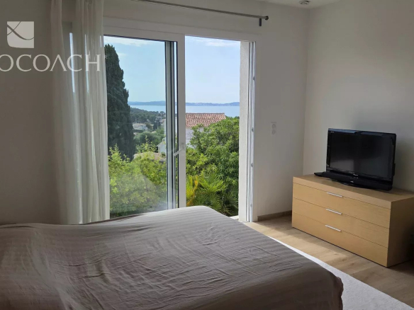 Chambre lumineuse avec vue sur la mer à Carqueiranne, mobilier moderne et télévision.