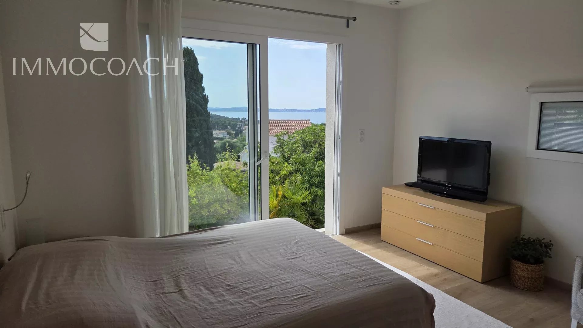 Chambre lumineuse avec vue sur la mer à Carqueiranne, mobilier moderne et télévision.