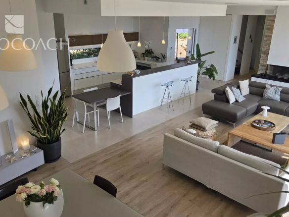 Intérieur d'une maison contemporaine avec vue sur la mer, salon et cuisine ouverte.