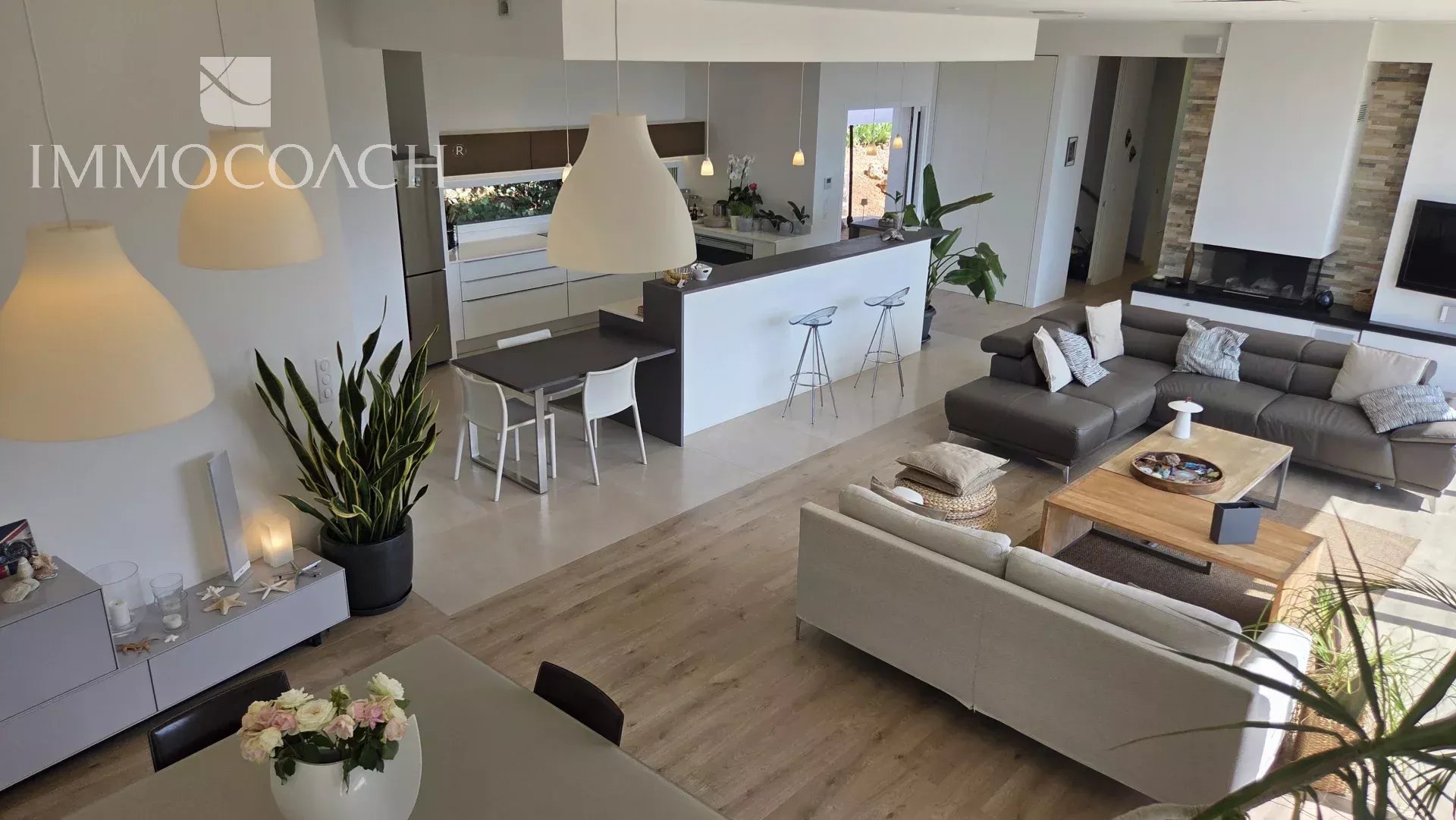 Intérieur d'une maison contemporaine avec vue sur la mer, salon et cuisine ouverte.