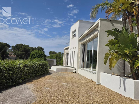 Maison contemporaine à Carqueiranne avec vue sur la mer et collines, entourée de verdure.