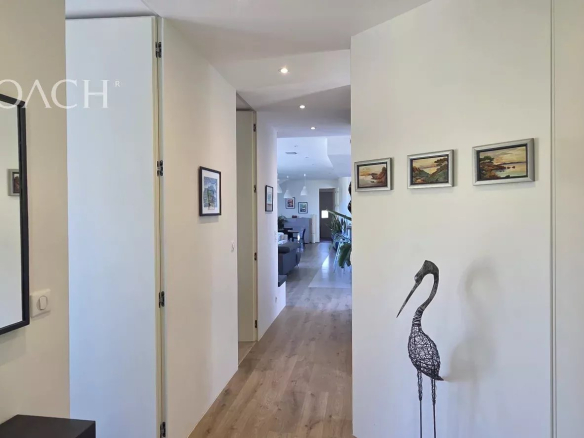 Intérieur d'une maison contemporaine avec un couloir et des œuvres d'art accrochées au mur.