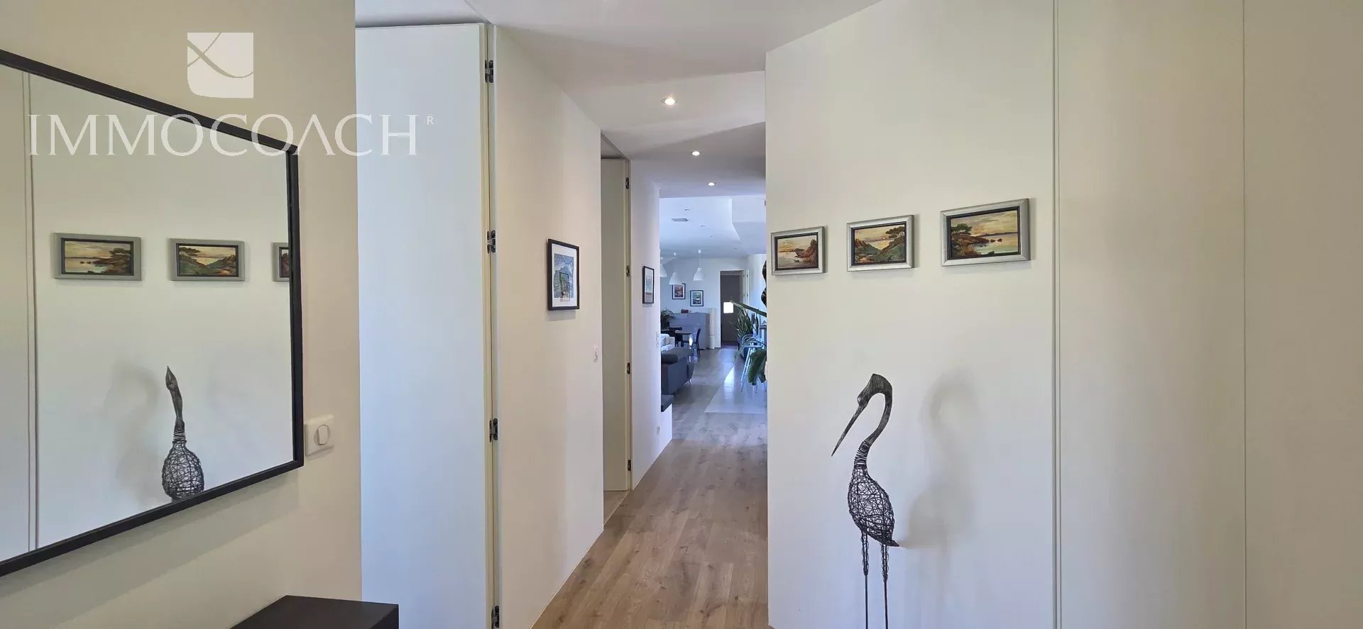 Intérieur d'une maison contemporaine avec un couloir et des œuvres d'art accrochées au mur.