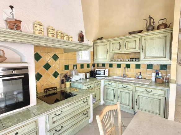 Kitchen of a villa in Carqueiranne with green wood furniture and yellow and green tiles.