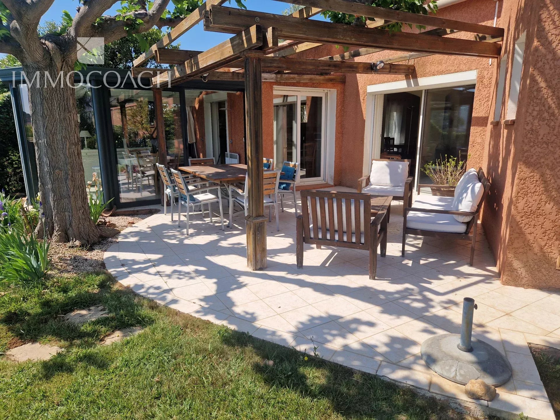 Villa with terrace and garden Sunny terrace of a villa with garden furniture and garden view.