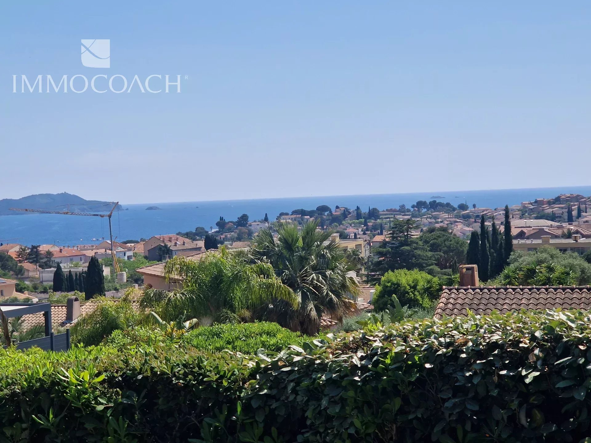 Sea view from a villa in Carqueiranne Sea view from a villa with garden in Carqueiranne, surrounded by houses and vegetation.