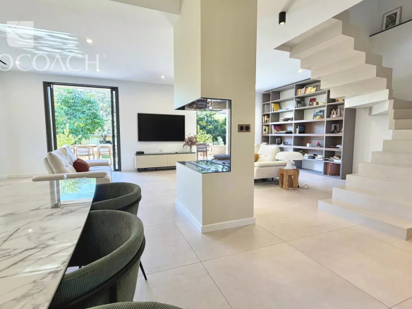 Intérieur d'une maison moderne avec un séjour lumineux, cuisine américaine et escalier design.