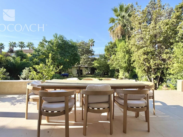 Terrasse d'une maison avec table et chaises, vue sur jardin verdoyant à Hyères.