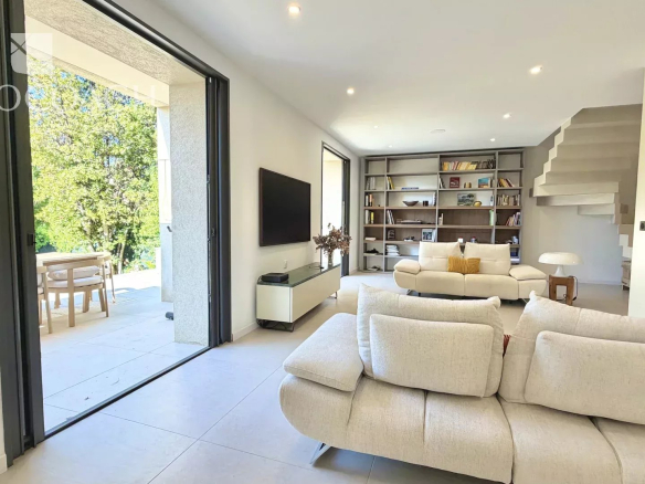 Intérieur d'une maison moderne avec salon lumineux et accès à l'extérieur.