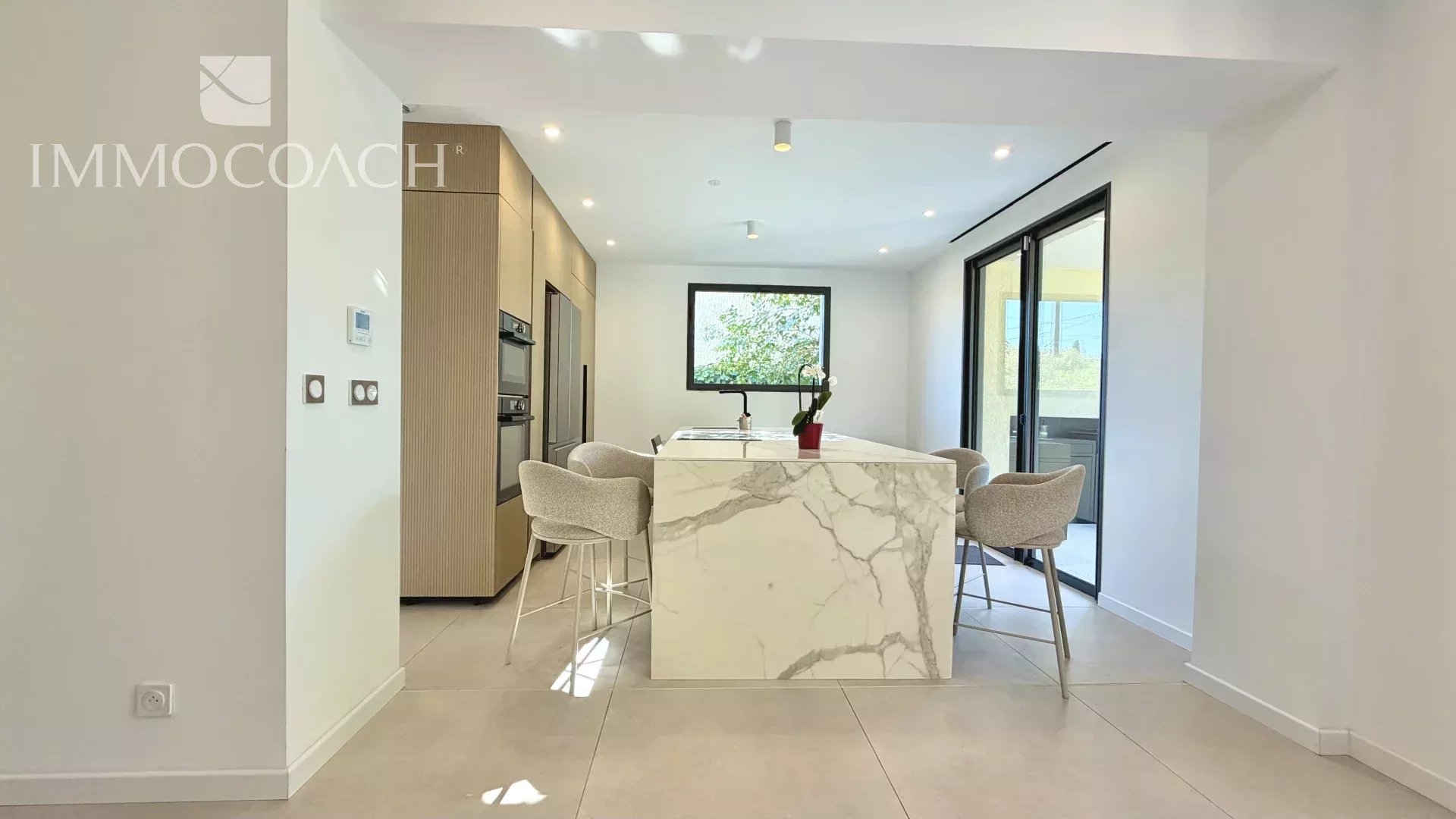 Cuisine moderne rénovée à Hyères Intérieur d'une cuisine moderne avec îlot central et chaises, lumière naturelle, rénovée en 2026 à Hyères.