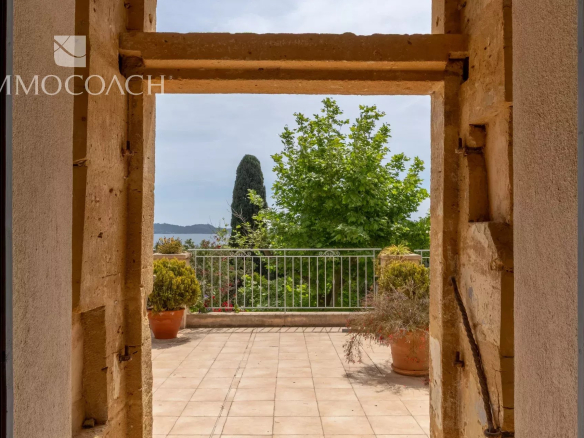 View from a window overlooking a garden and trees, with a visible balustrade.