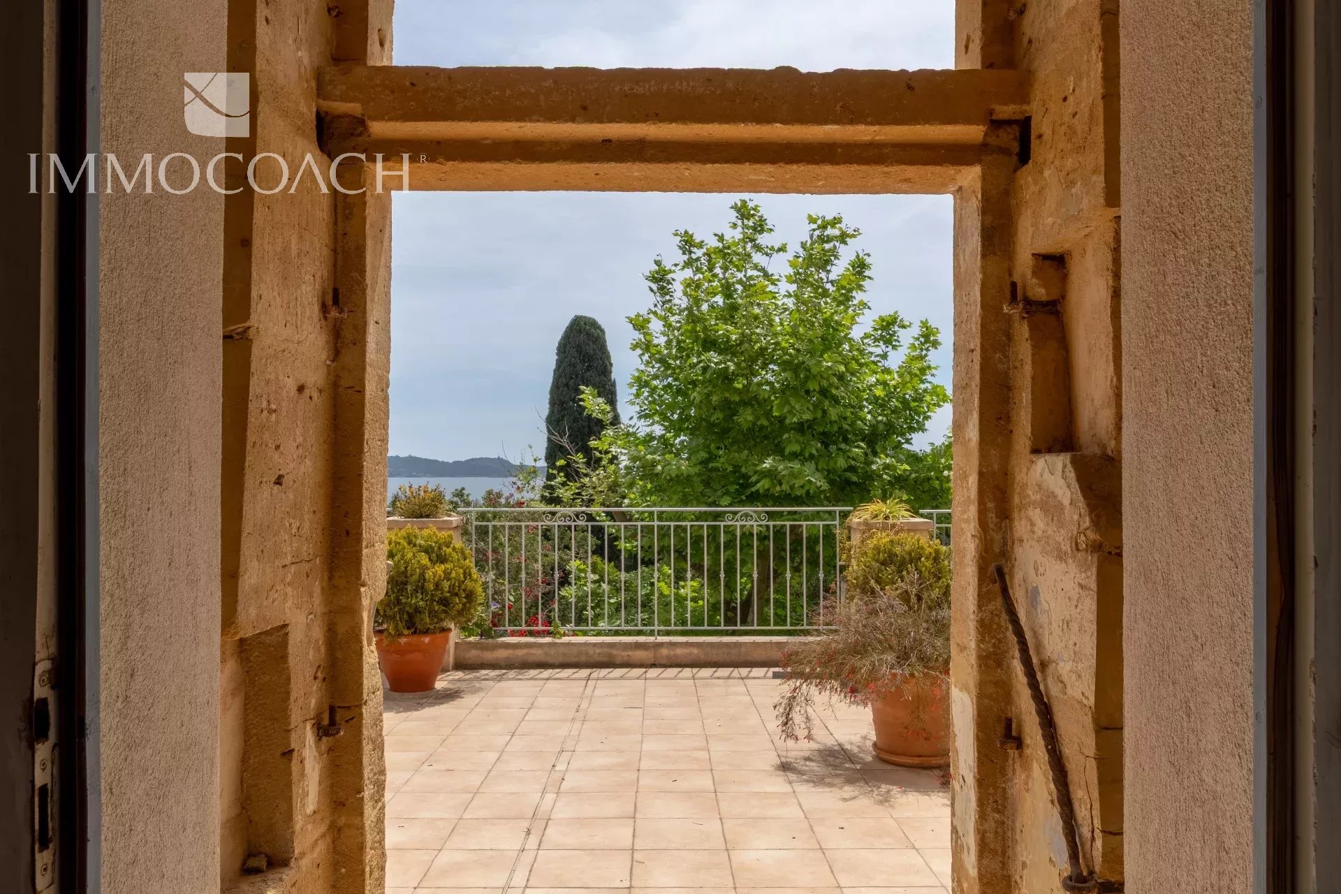 View from a window overlooking a garden and trees, with a visible balustrade.