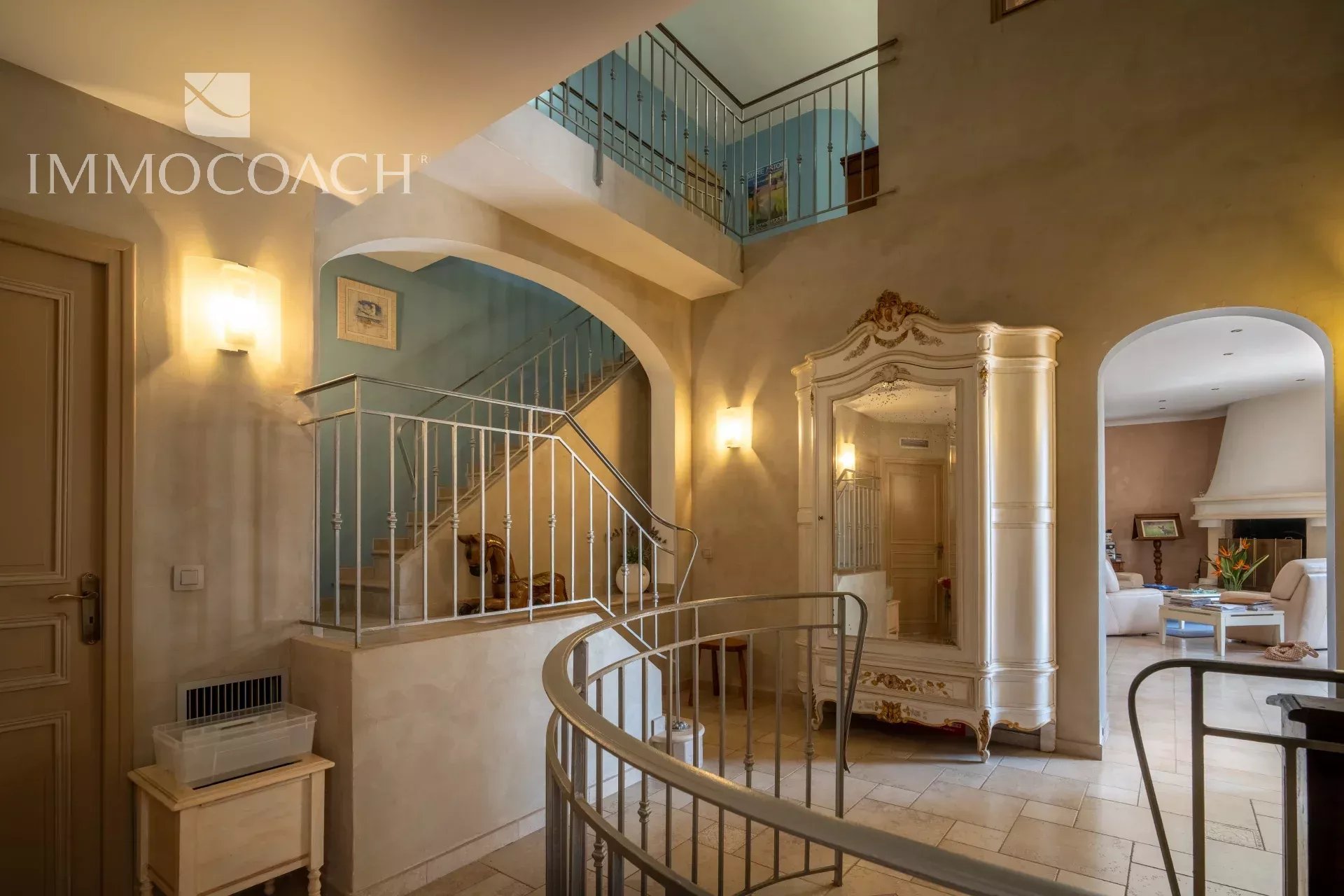 Interior of a property with a staircase and a large mirror, decorated in light colors.