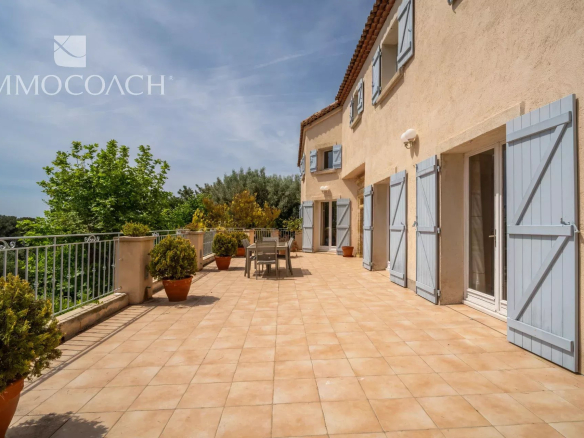 Sunny terrace of a property in Carqueiranne with sea view and garden furniture.