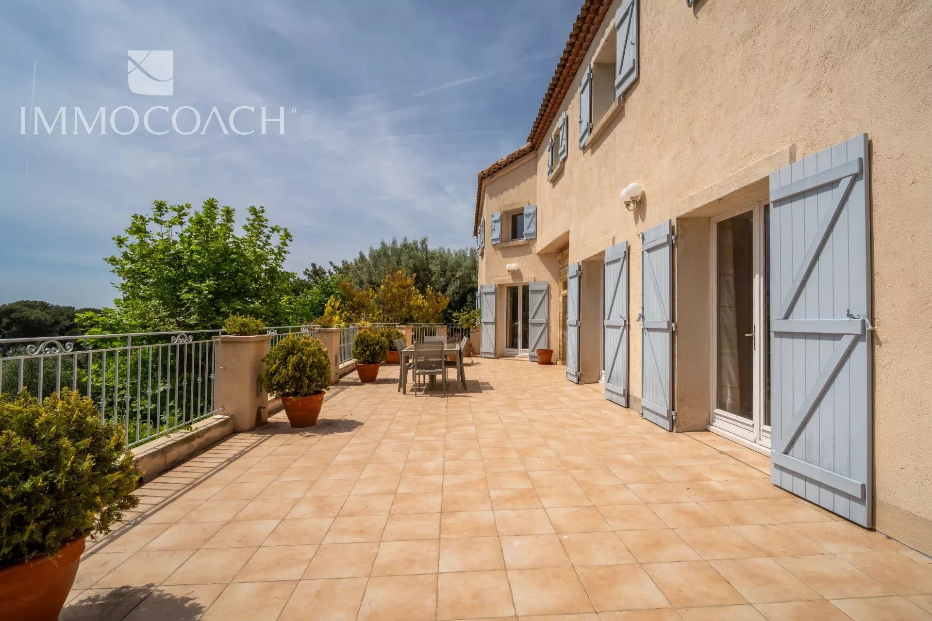 Sunny terrace of a property in Carqueiranne with sea view and garden furniture.