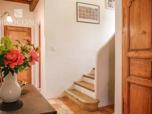 Interior of a bastide with a staircase and plaster walls, decorated with flowers.