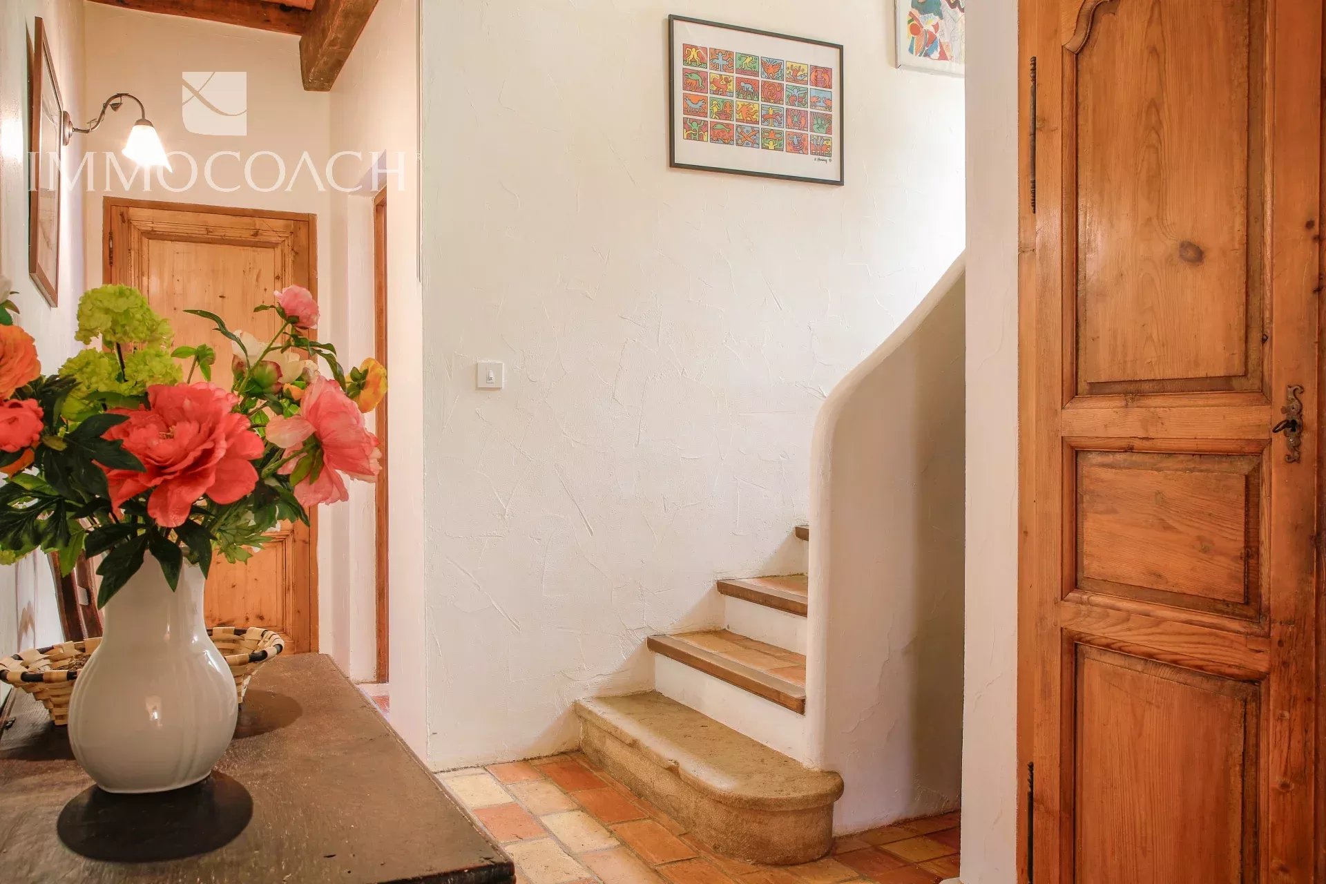 Interior of a country house in Collobrières Interior of a bastide with a staircase and plaster walls, decorated with flowers.