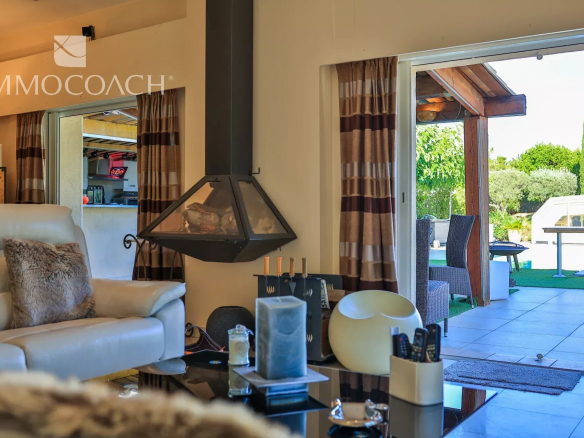 Intérieur d'une villa moderne avec cheminée, salon et accès à la terrasse.