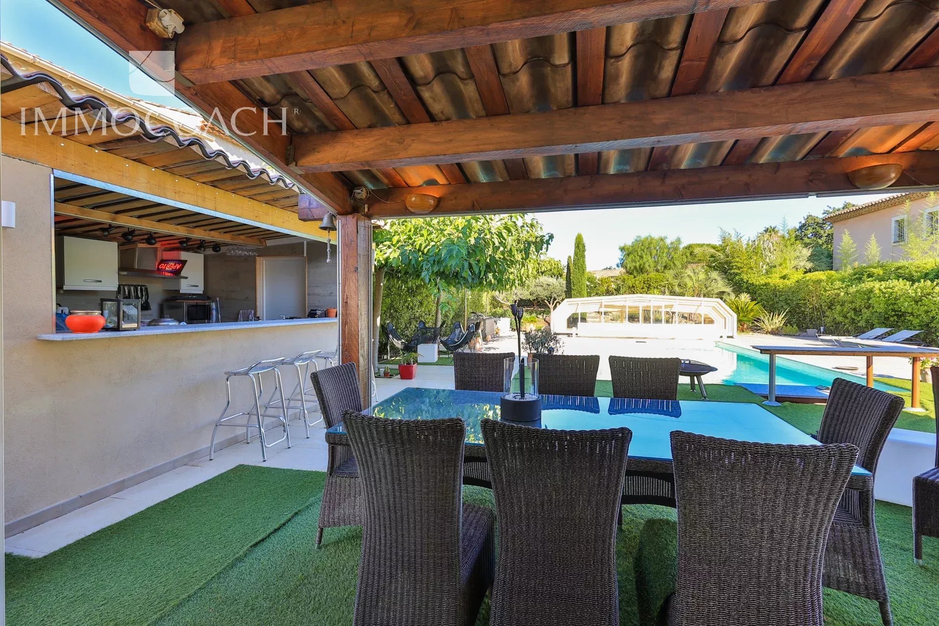 Terrasse de villa à Saint-Tropez Terrasse couverte avec table et chaises, piscine et jardin en arrière-plan.