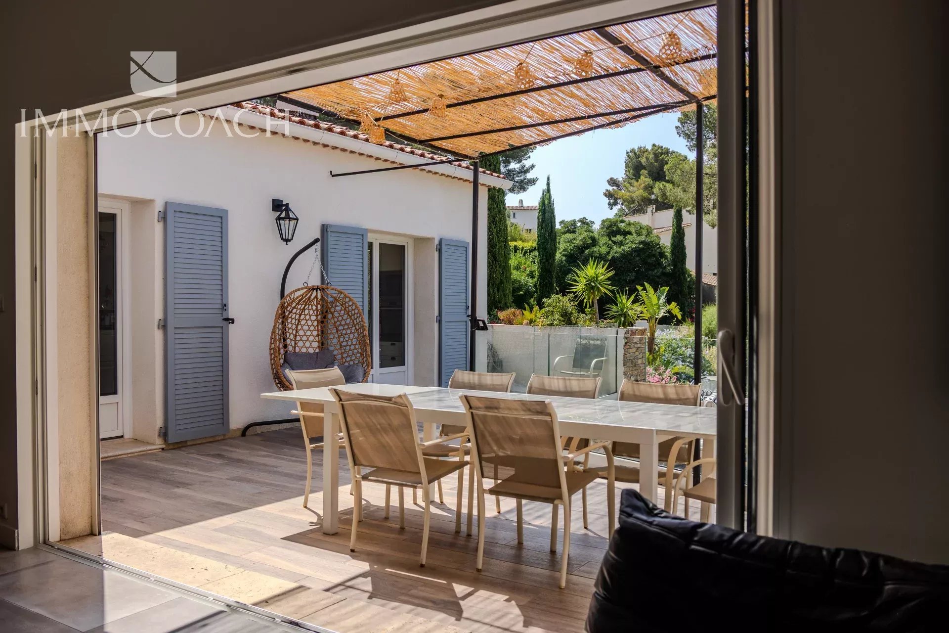 Terrasse d'une maison rénovée à Carqueiranne avec mobilier moderne et verdure.