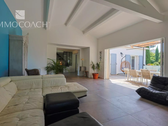 Intérieur d'une maison rénovée à Carqueiranne avec un salon moderne et une terrasse visible.