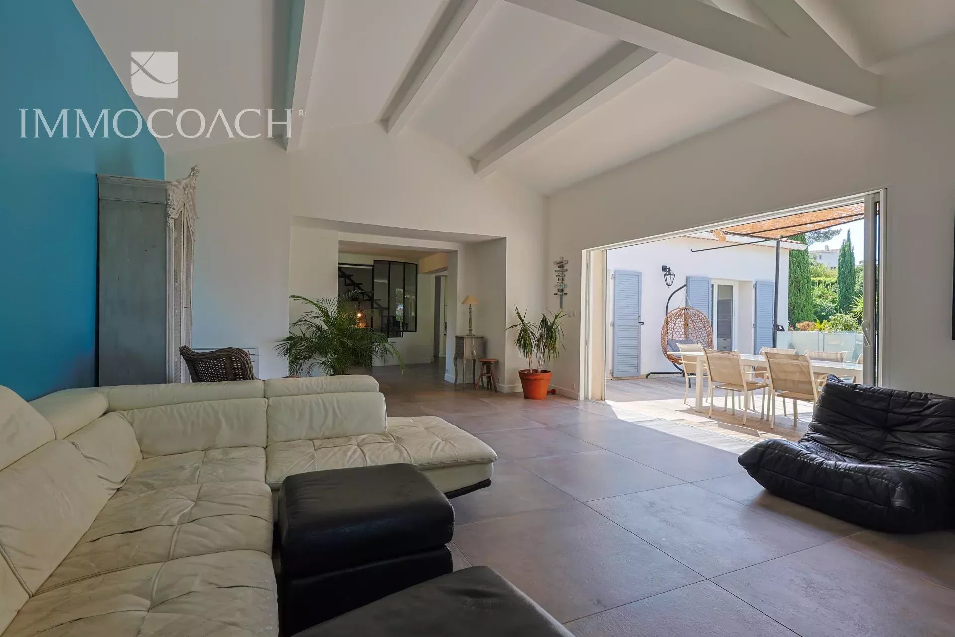 Intérieur d'une maison rénovée à Carqueiranne avec un salon moderne et une terrasse visible.